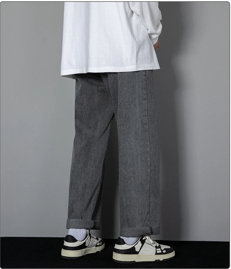 Person wearing gray pants and a white shirt against a gray background