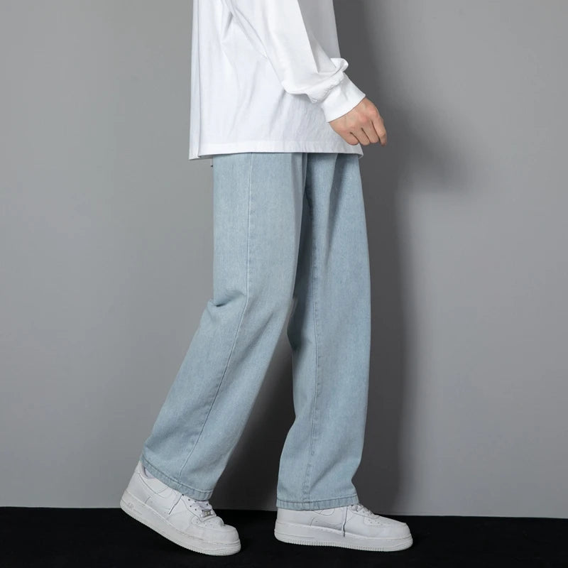 Person wearing light blue jeans and white sneakers against a gray background