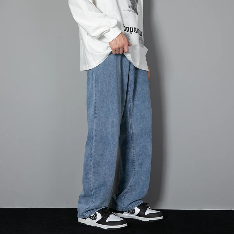 Person wearing a white long-sleeve shirt, blue jeans, and black and white sneakers against a gray background