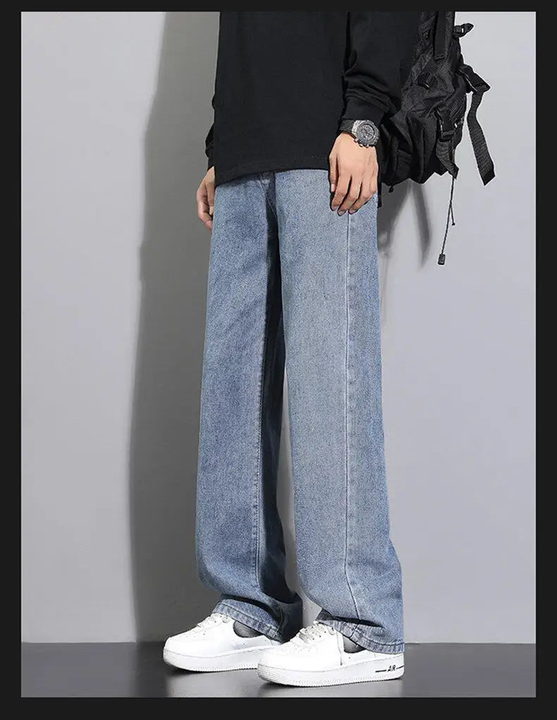 Person wearing light blue jeans and white sneakers on a plain background