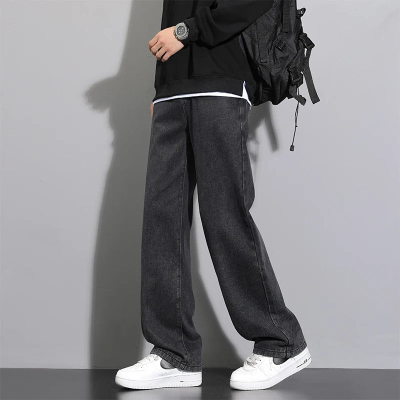 Person wearing black jeans and a black jacket with a backpack on a gray background
