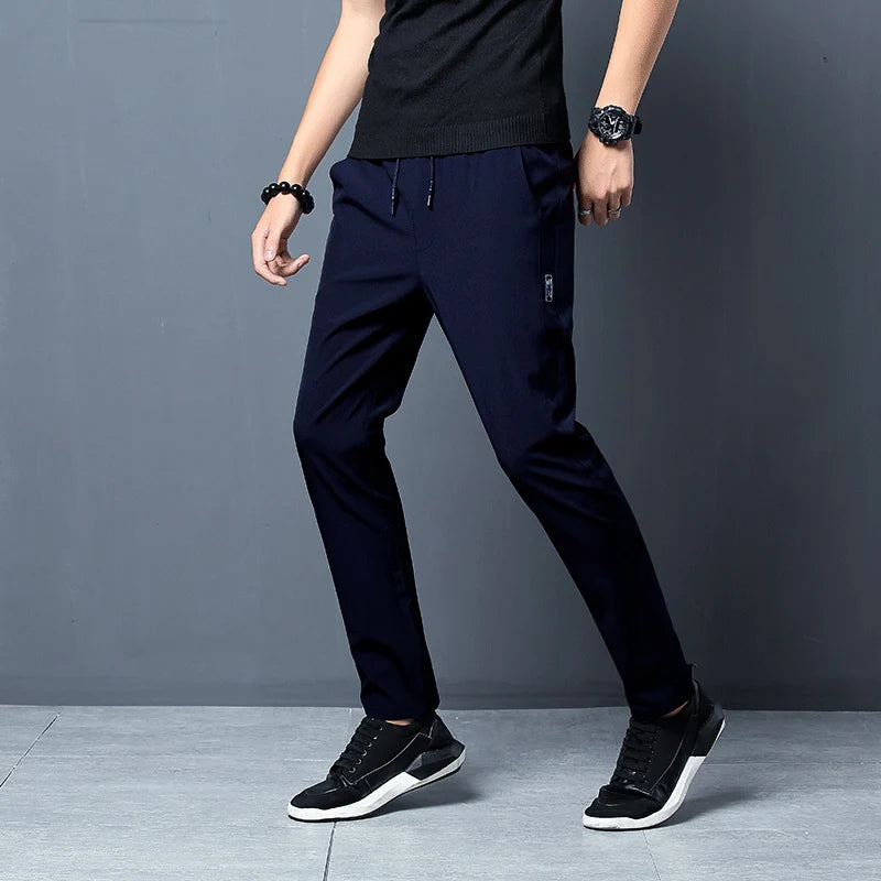Person wearing navy blue pants and black shoes on a gray background