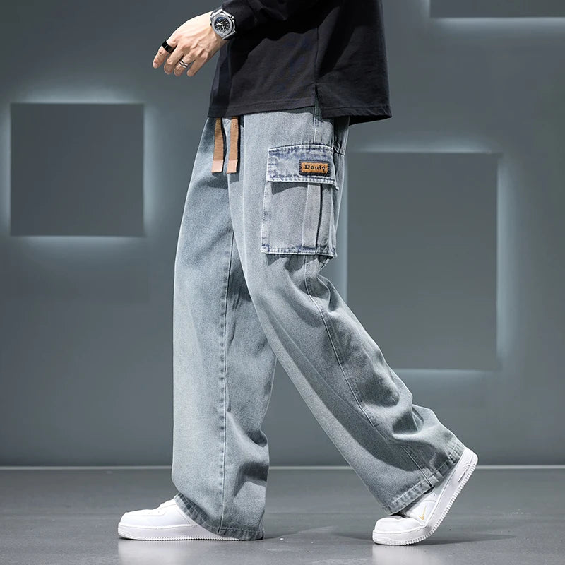 Person wearing light blue jeans and white sneakers on a gray background