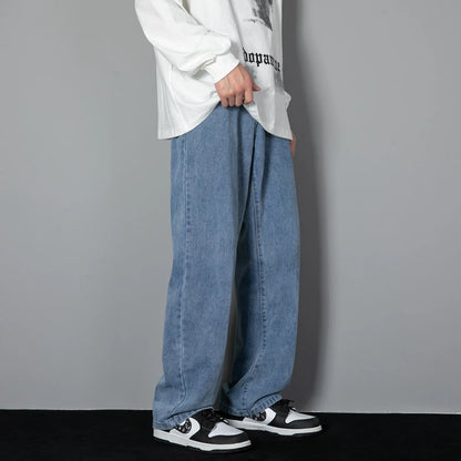 Person wearing a white long-sleeve shirt, blue jeans, and black and white sneakers against a gray background