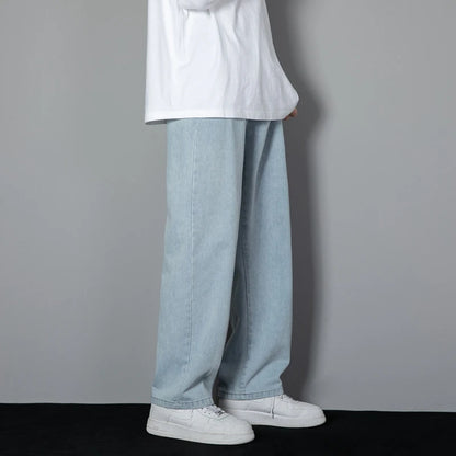 Person wearing light blue jeans and white sneakers against a gray background