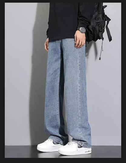 Person wearing light blue jeans and white sneakers on a plain background