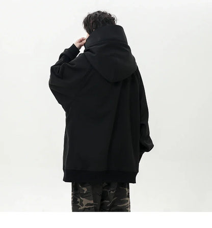 Person wearing a black oversized hoodie with camouflage pants on a white background