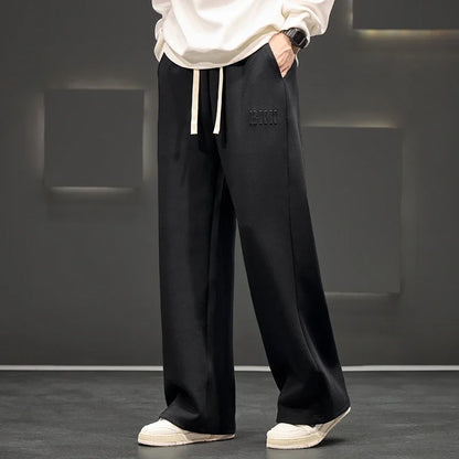 Person wearing black pants with a brand logo against a gray background