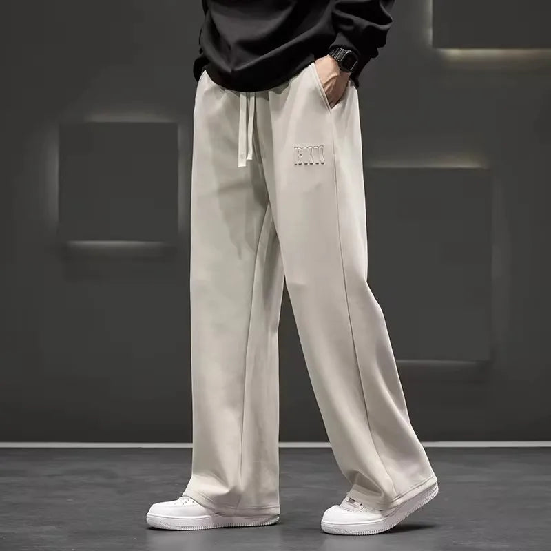 Person wearing light gray pants with a brand logo against a dark background