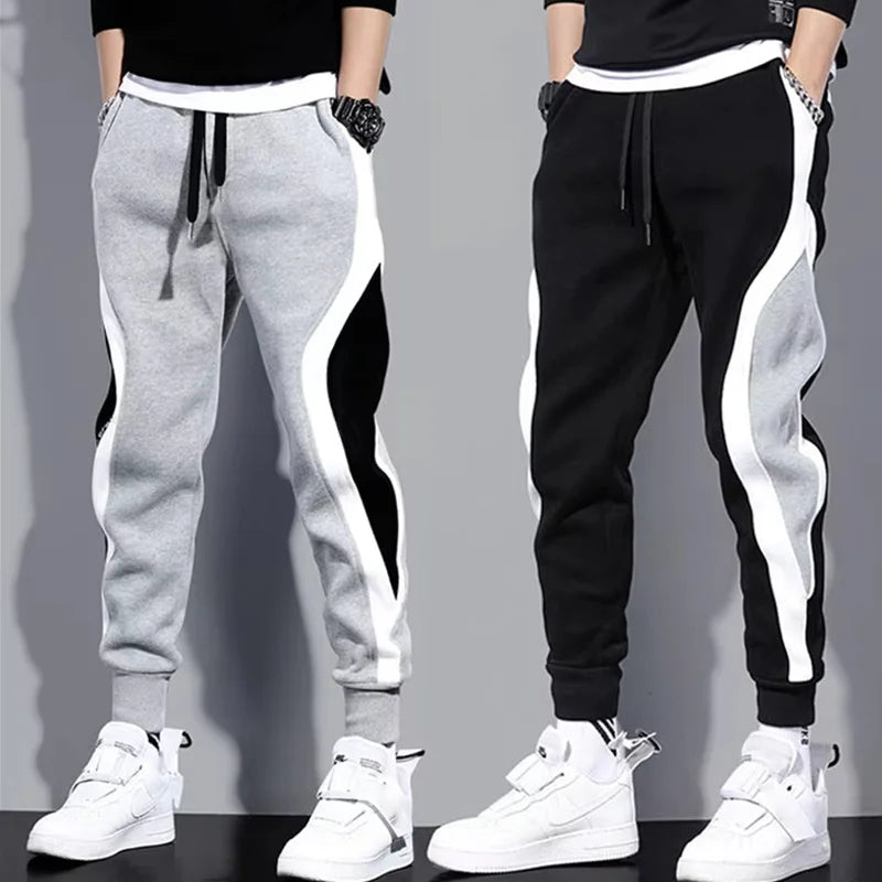 Two pairs of jogger pants, one gray and one black, with white side stripes, worn by models against a gray background.