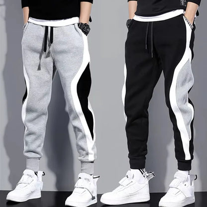 Two pairs of jogger pants, one gray and one black, with white side stripes, worn by models against a gray background.