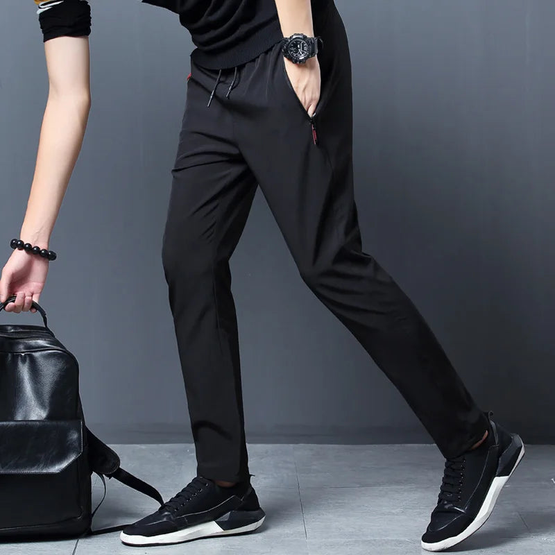 Person wearing black pants and shoes with a black backpack on a gray background