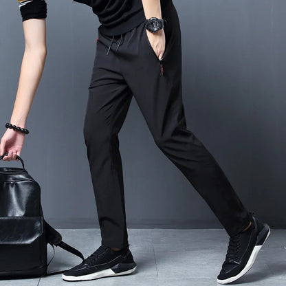 Person wearing black pants and shoes with a black backpack on a gray background