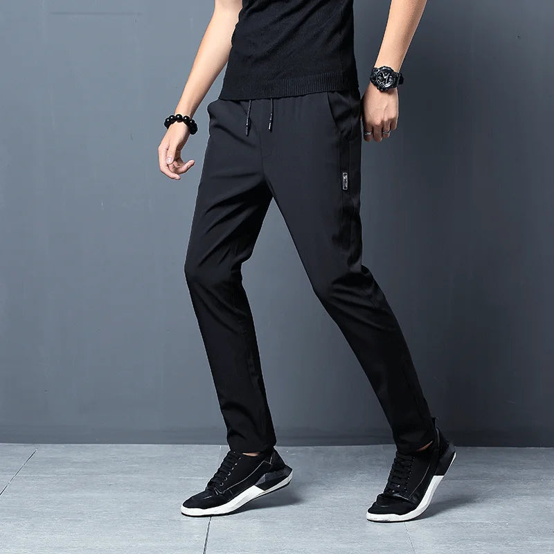Person wearing black pants and black sneakers on a gray background