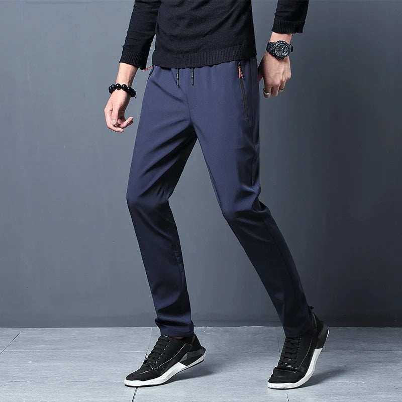 Person wearing navy blue pants and black sneakers on a gray background