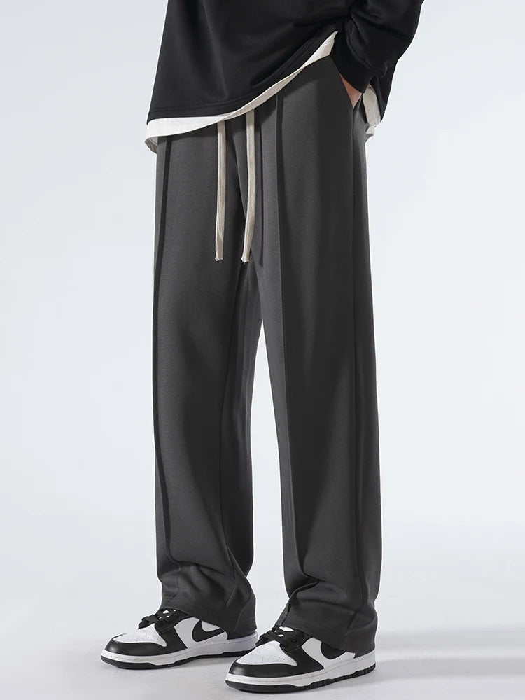 Person wearing black pants with a white drawstring on a light gray background