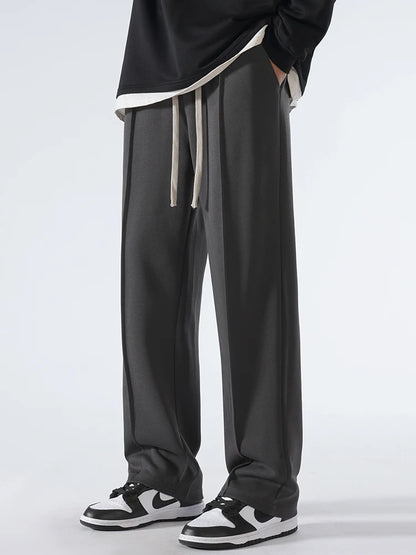 Person wearing black pants with a white drawstring on a light gray background