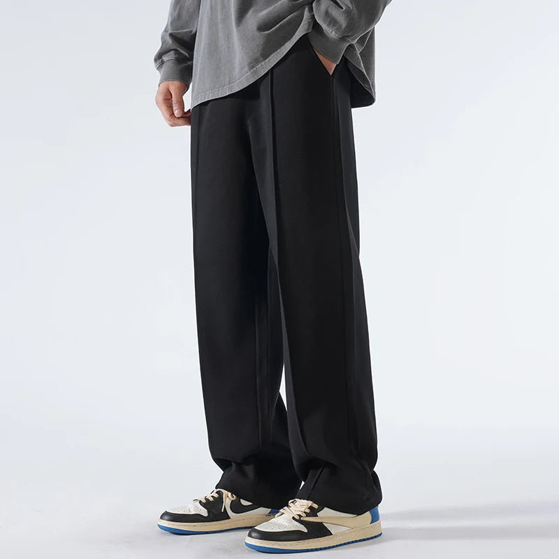 Person wearing black wide-leg pants with a gray shirt on a white background