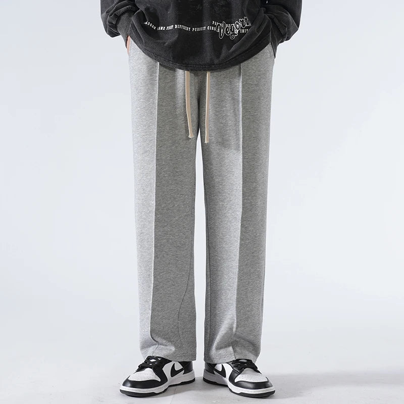 Person wearing gray sweatpants and black sneakers on a white background
