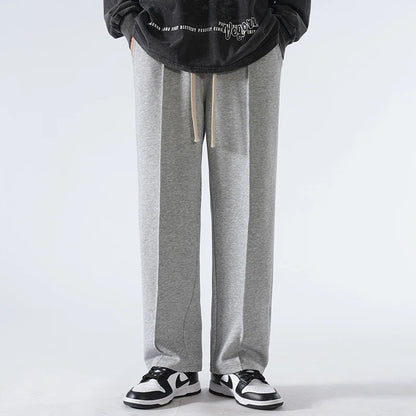 Person wearing gray sweatpants and black sneakers on a white background