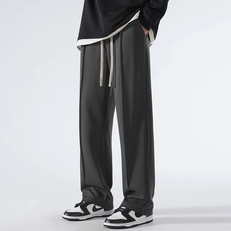 Person wearing black pants with a white drawstring on a light gray background