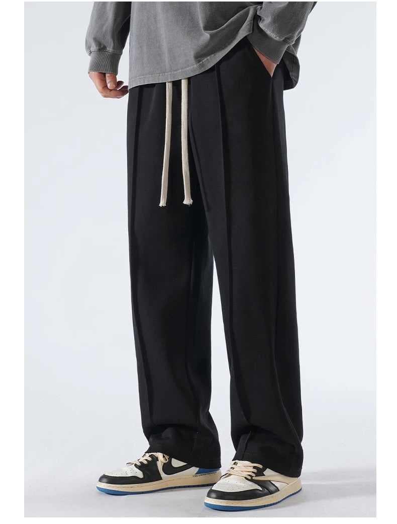 Person wearing black wide-leg pants with a gray sweatshirt on a white background